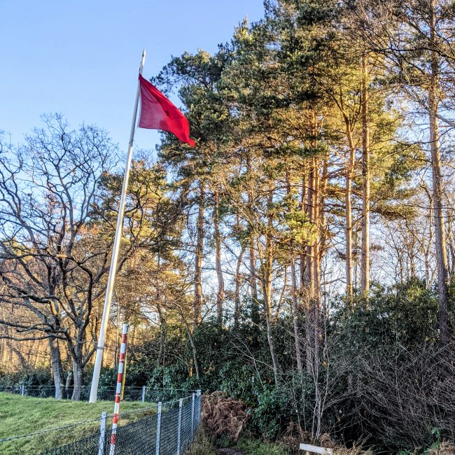 A red flag representing firing in progress within Ash Ranges